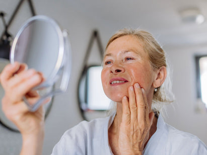 woman looking at her face in a mirror