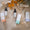 Three Alexandra Kay oil bottles and boxes (Time to Smile, Relax, Sleep) on a beige knit sweater with orange leaves and The Vegan Society logo.