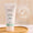 A white tube of Green People Fruit Scrub Exfoliator stands on a wooden tray next to a Dermatologically Tested icon.