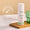 Eine weiße Flasche Green People Day Solution Cream LSF15 steht auf einem Holztablett neben einem gerippten grünen Glasgefäß.
