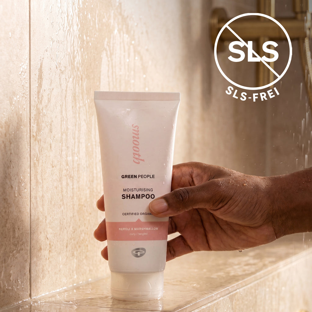 Eine Hand hält das Green People Feuchtigkeitsshampoo unter der Dusche, daneben der Hinweis SLS-frei.