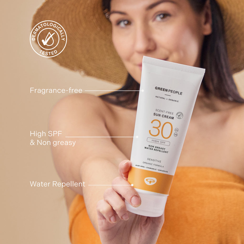 Una mujer con sombrero para el sol sostiene un tubo de Crema Solar sin Fragancia SPF30 de 200 ml con texto que resalta su fórmula orgánica y sin fragancia.