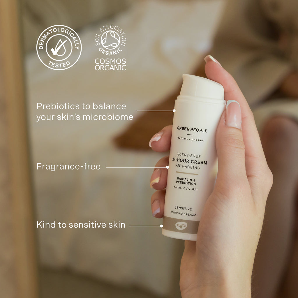 Una mano sostiene un frasco de Green People Scent Free 24-Hour Cream, etiquetada como orgánica certificada, sin fragancia e hipoalergénica.