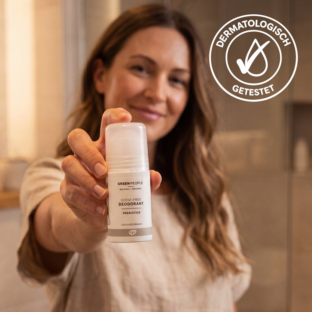 Eine Frau hält das parfümfreie Deodorant von Green People (75 ml), daneben das Siegel Dermatologisch getestet.