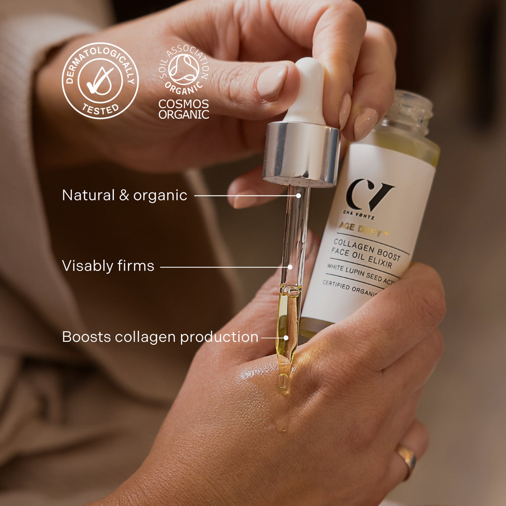 Manos usando un gotero de vidrio para aplicar el elixir de aceite facial Age Defy+ Collagen Boost a la piel.