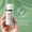Eine Hand hält eine Flasche Age Defy+ Getönte DD Creme LSF 15 vor grünem Hintergrund mit dermatologisch getestetem Siegel.
