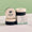 Tres tarros redondos negros y beige de Green People ONE Balm exhibidos junto a su caja de producto con marca sobre una superficie de mármol.