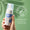 Eine Hand hält eine Flasche Oy Clear Skin Foaming Face Wash vor hellgrünem Hintergrund mit einem "Dermatologisch getestet"-Siegel.